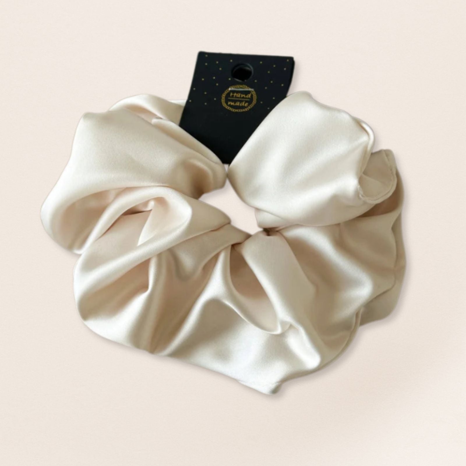 Cream-colored satin scrunchie for fine hair on a beige background