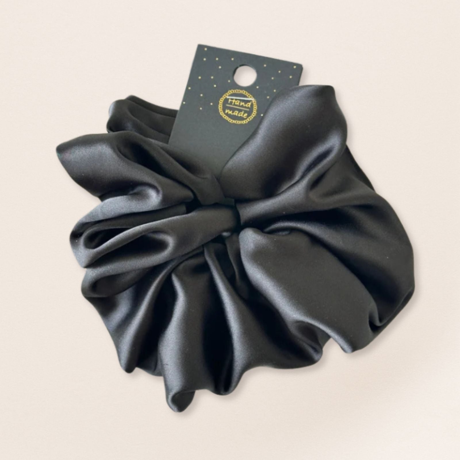 Black satin scrunchie for fine hair on a beige background