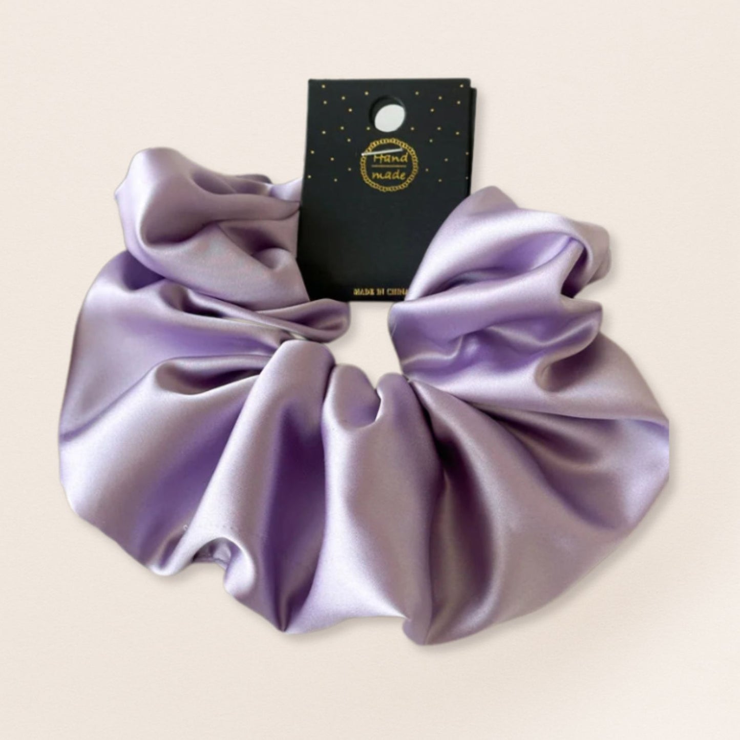 Purple satin scrunchie for fine hair on a beige background