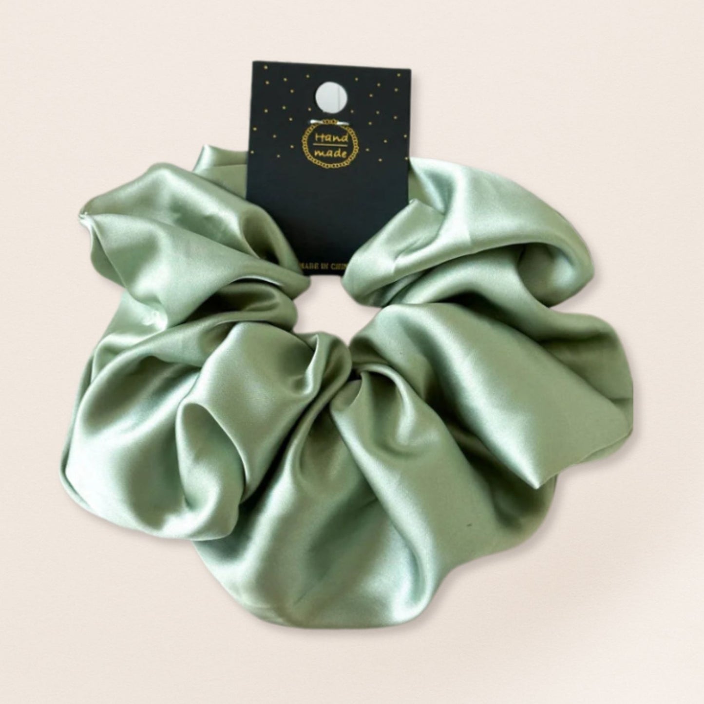 Green satin scrunchie for fine hair on a beige background