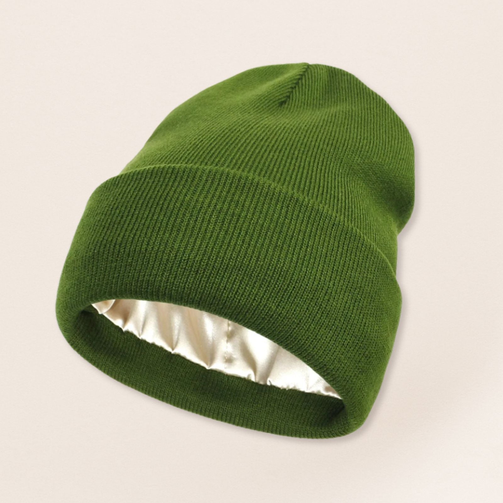 Green beanie with satin interior on a beige background