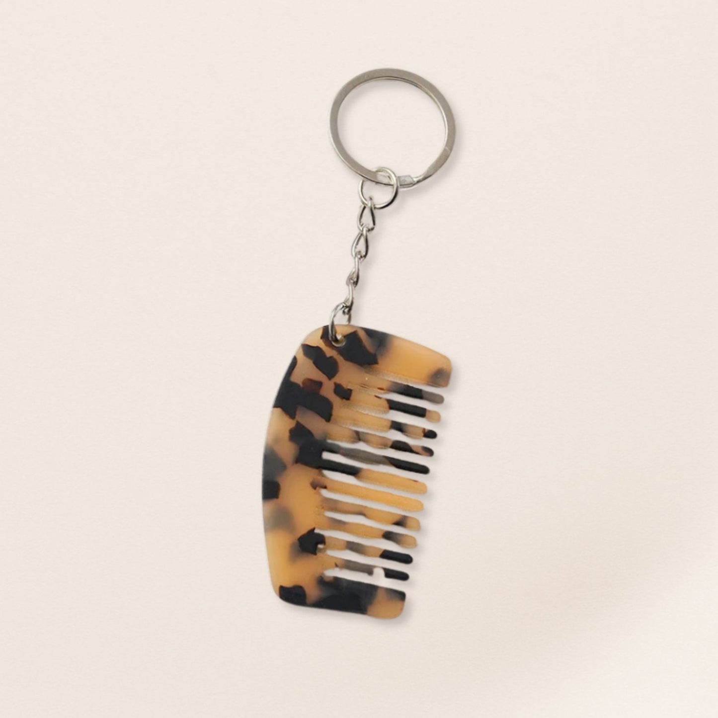 Tortoiseshell-patterned comb keychain on a beige background
