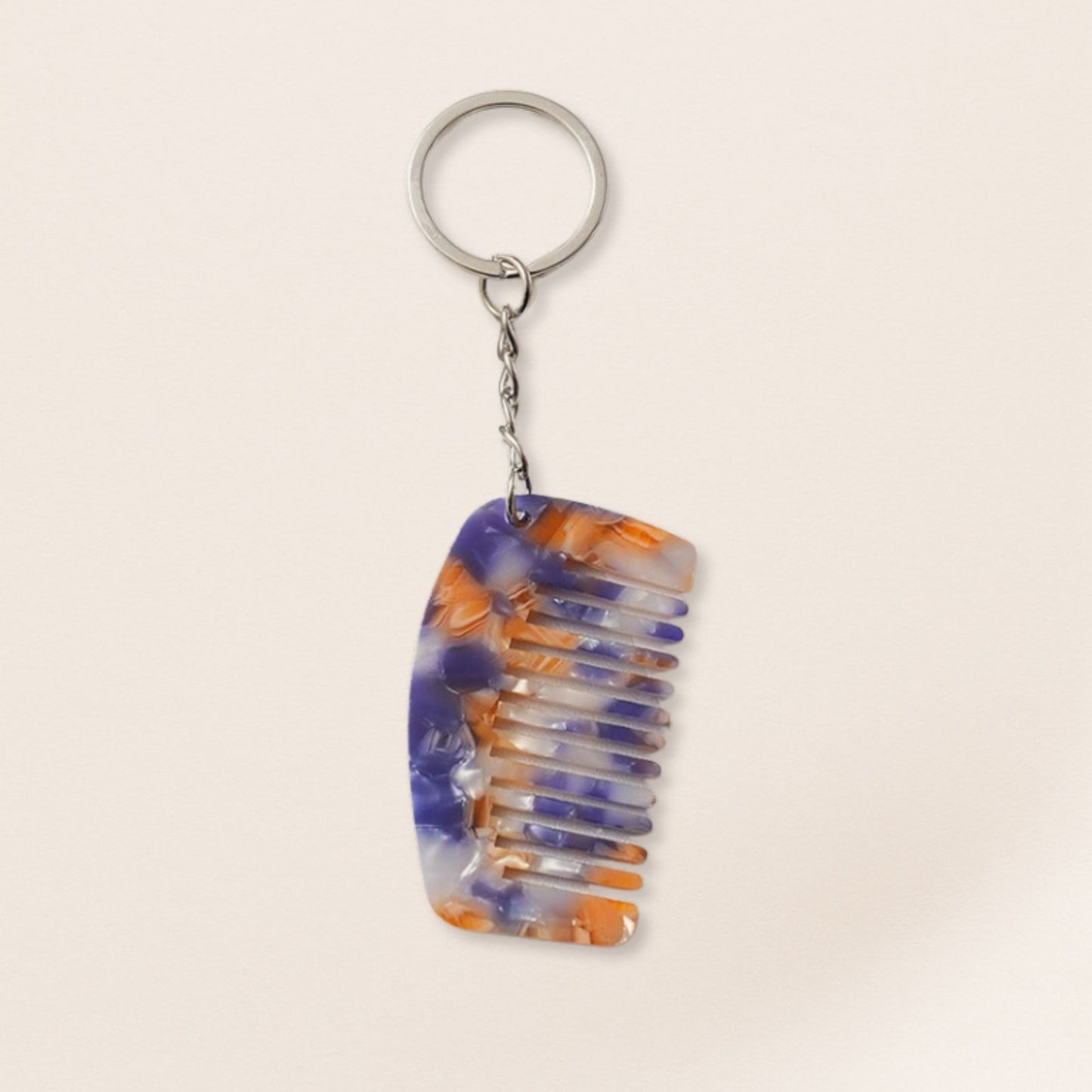 Colorful comb-shaped keychain on a beige background