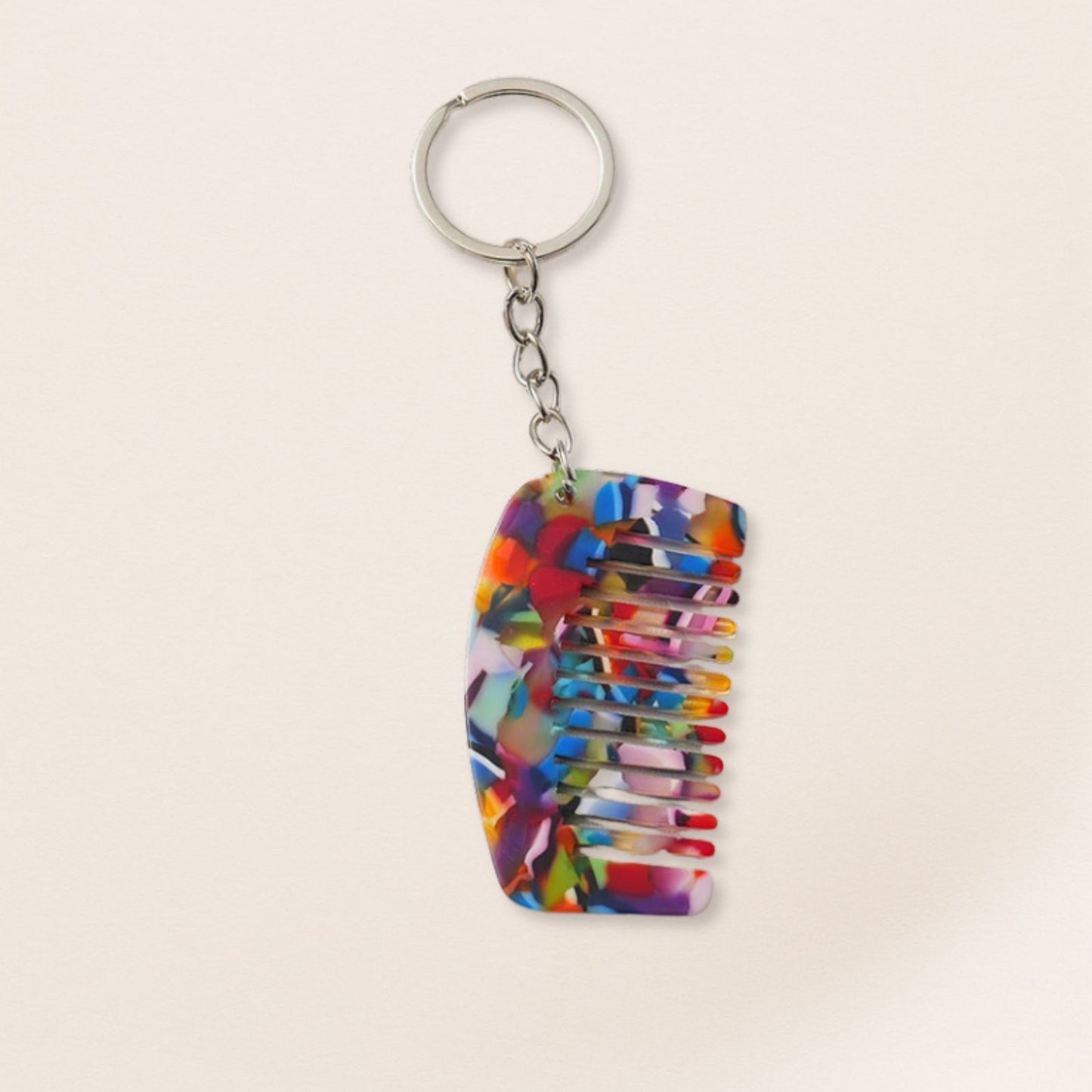 Colorful comb-shaped keychain on a beige background