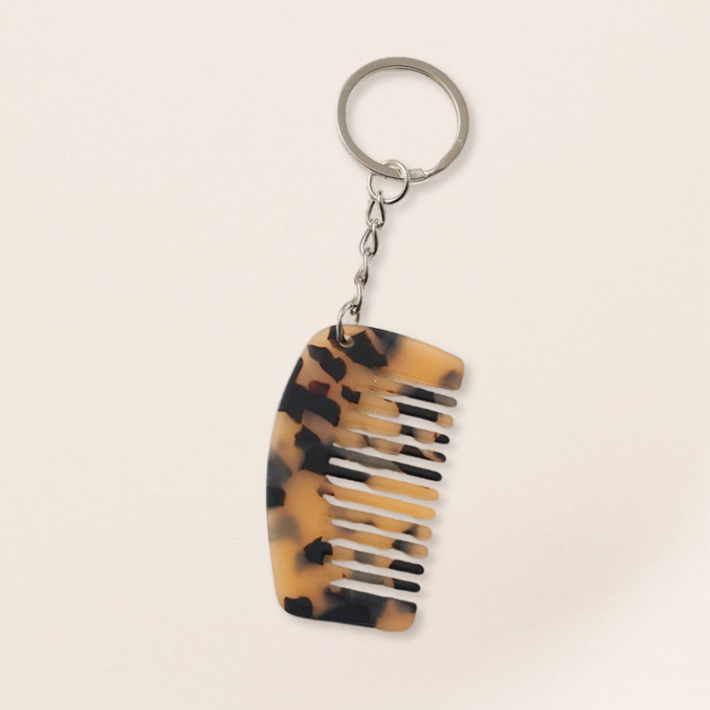 Tortoiseshell-patterned comb keychain on a beige background