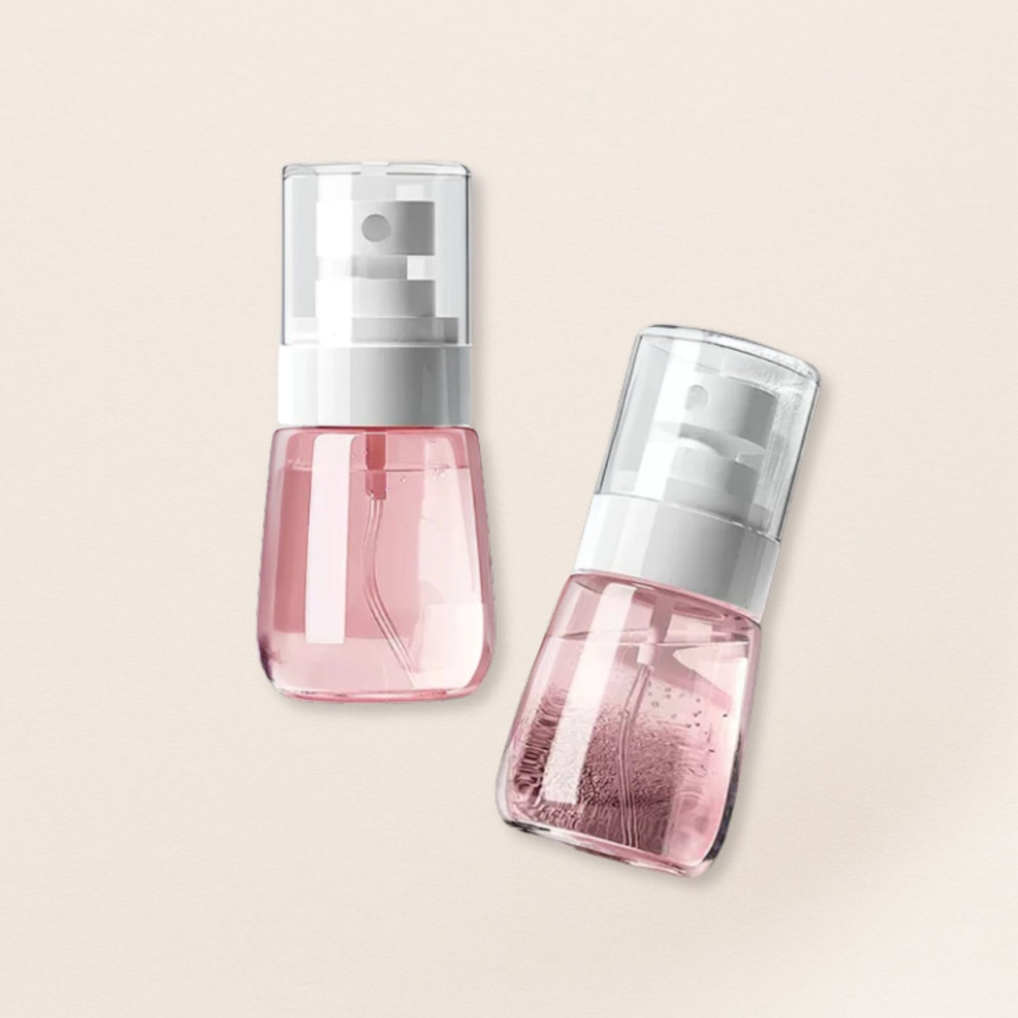 Two pink spray skincare bottles with silver caps on a beige background