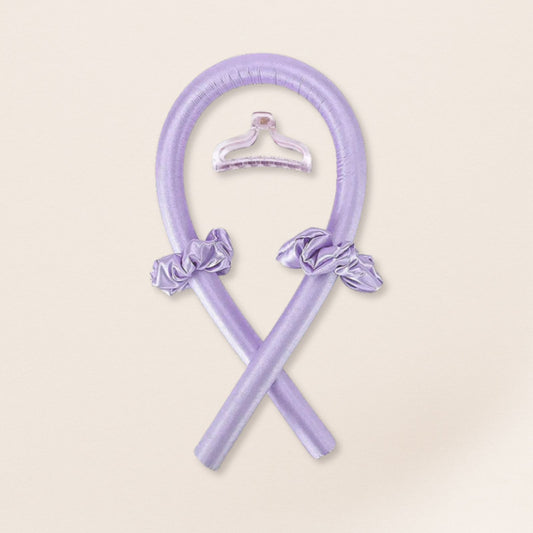 Lilac heatless curling set with matching satin scrunchies and a translucent clip on a beige background