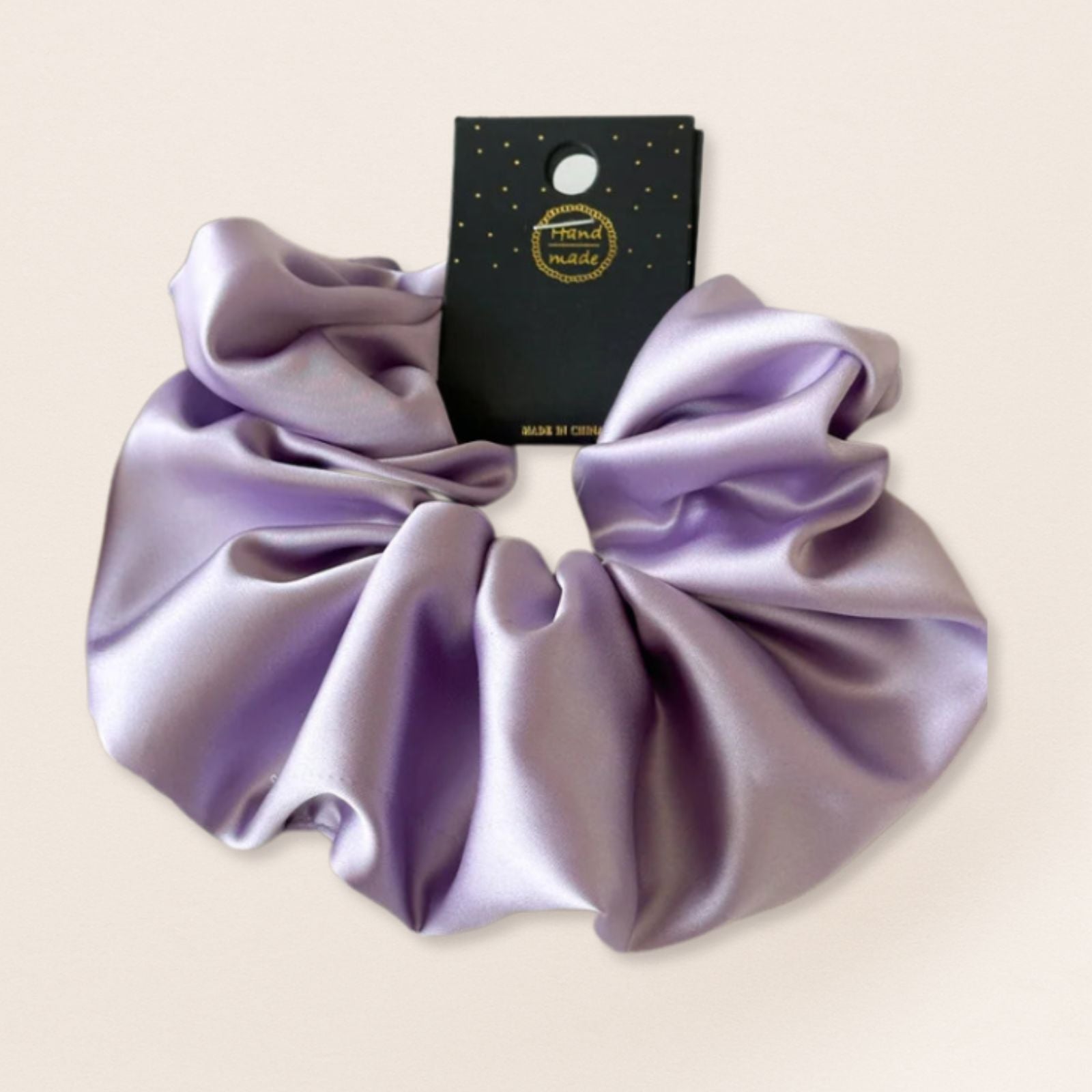 Purple satin scrunchie for fine hair on a beige background 