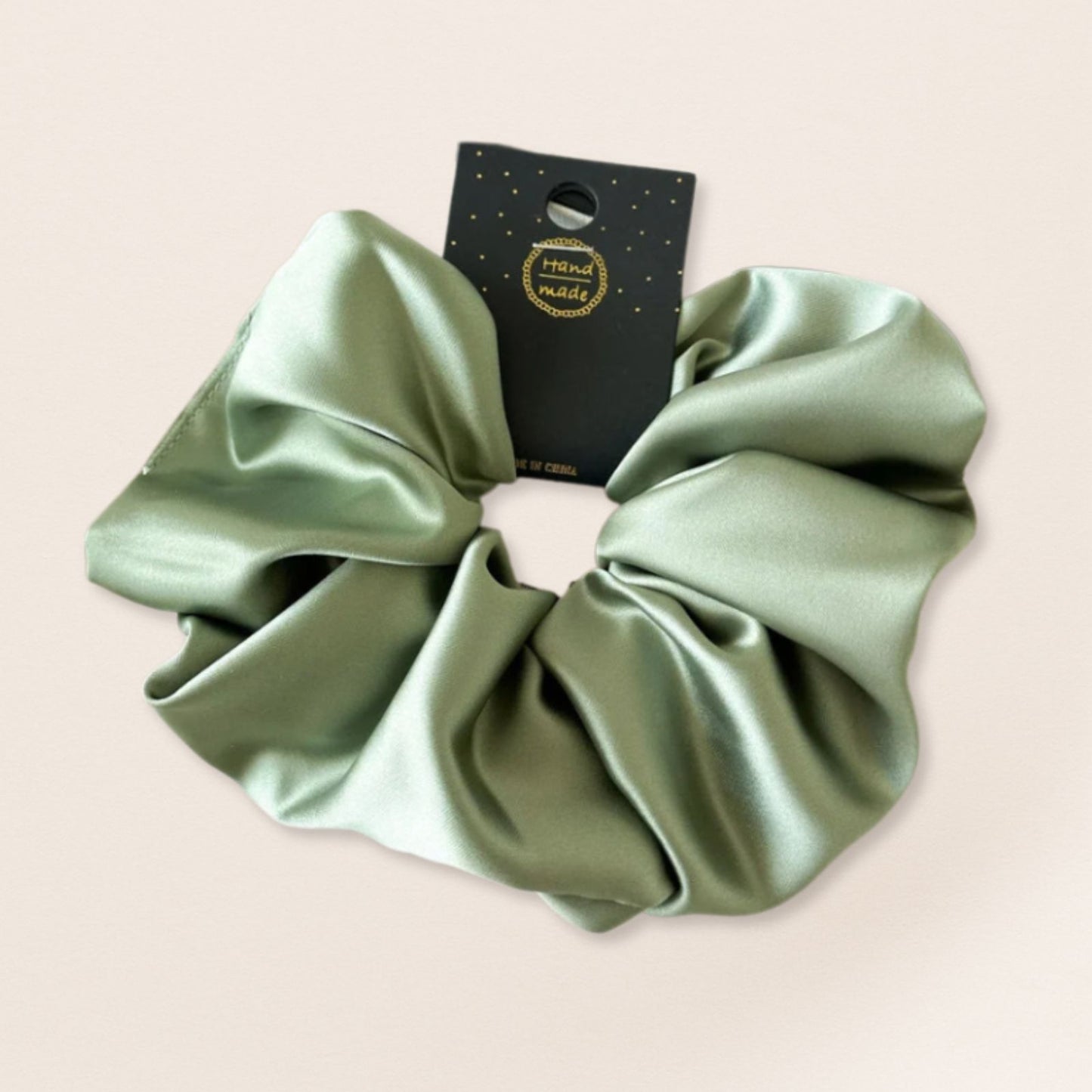 Green satin scrunchie for fine hair on a beige background