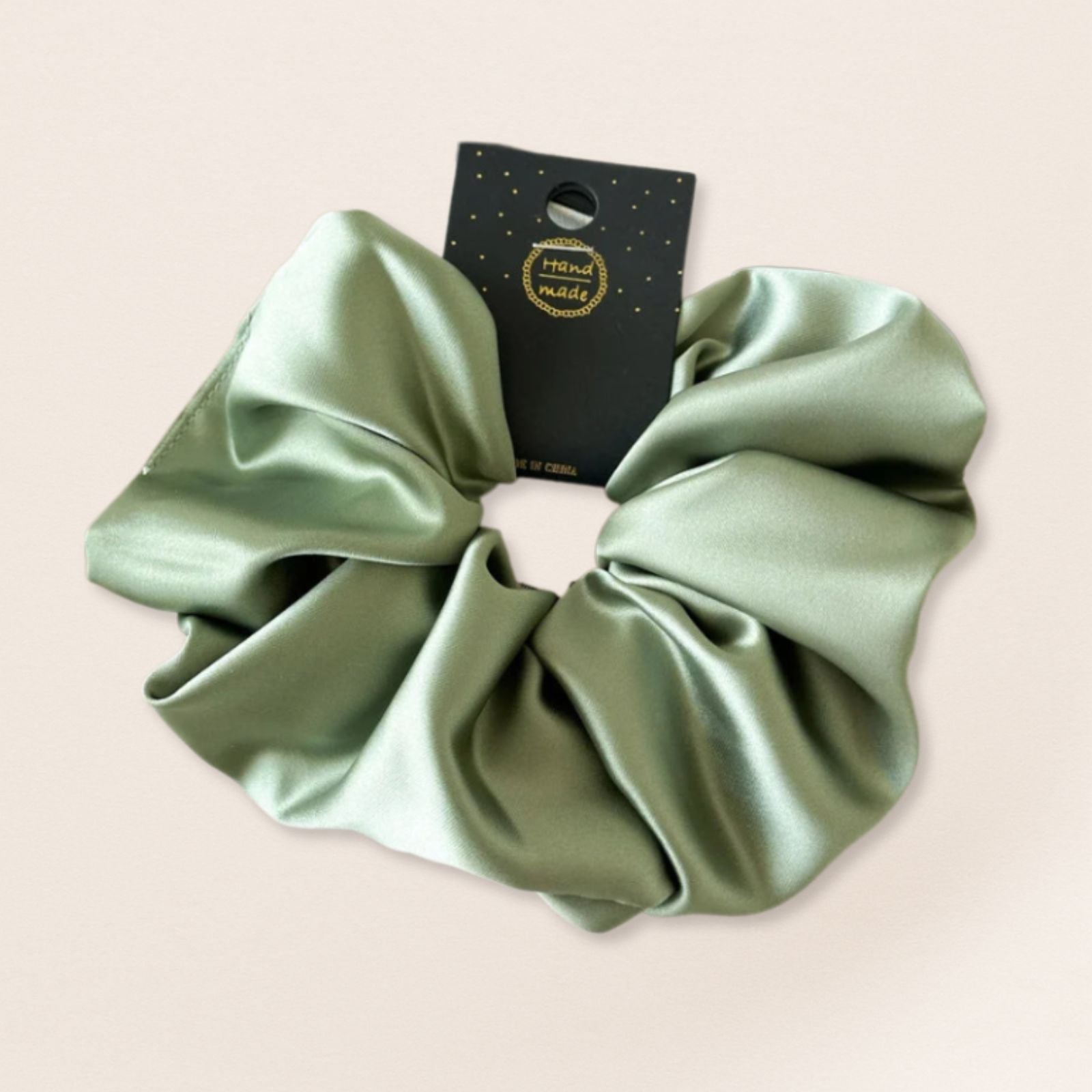 Green satin scrunchie for fine hair on a beige background
