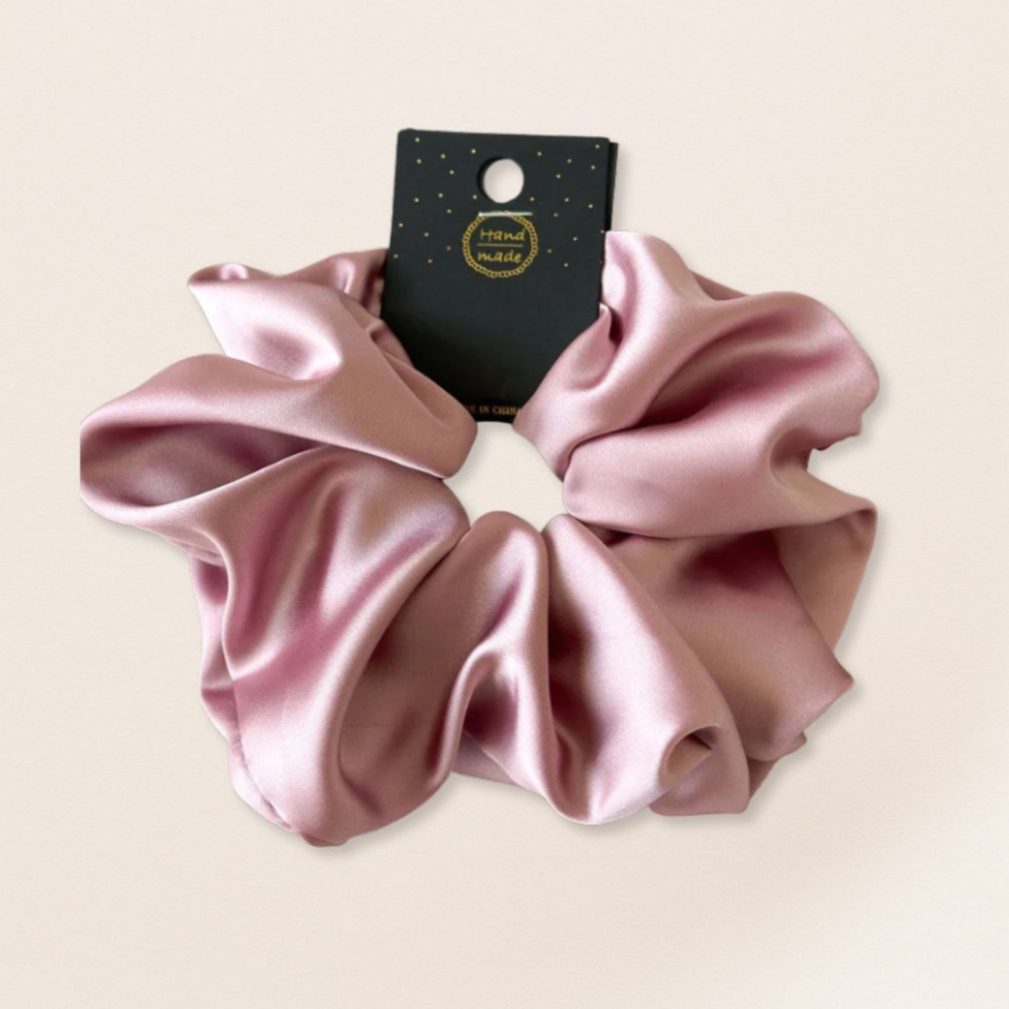 Pink satin scrunchie for fine hair on a beige background