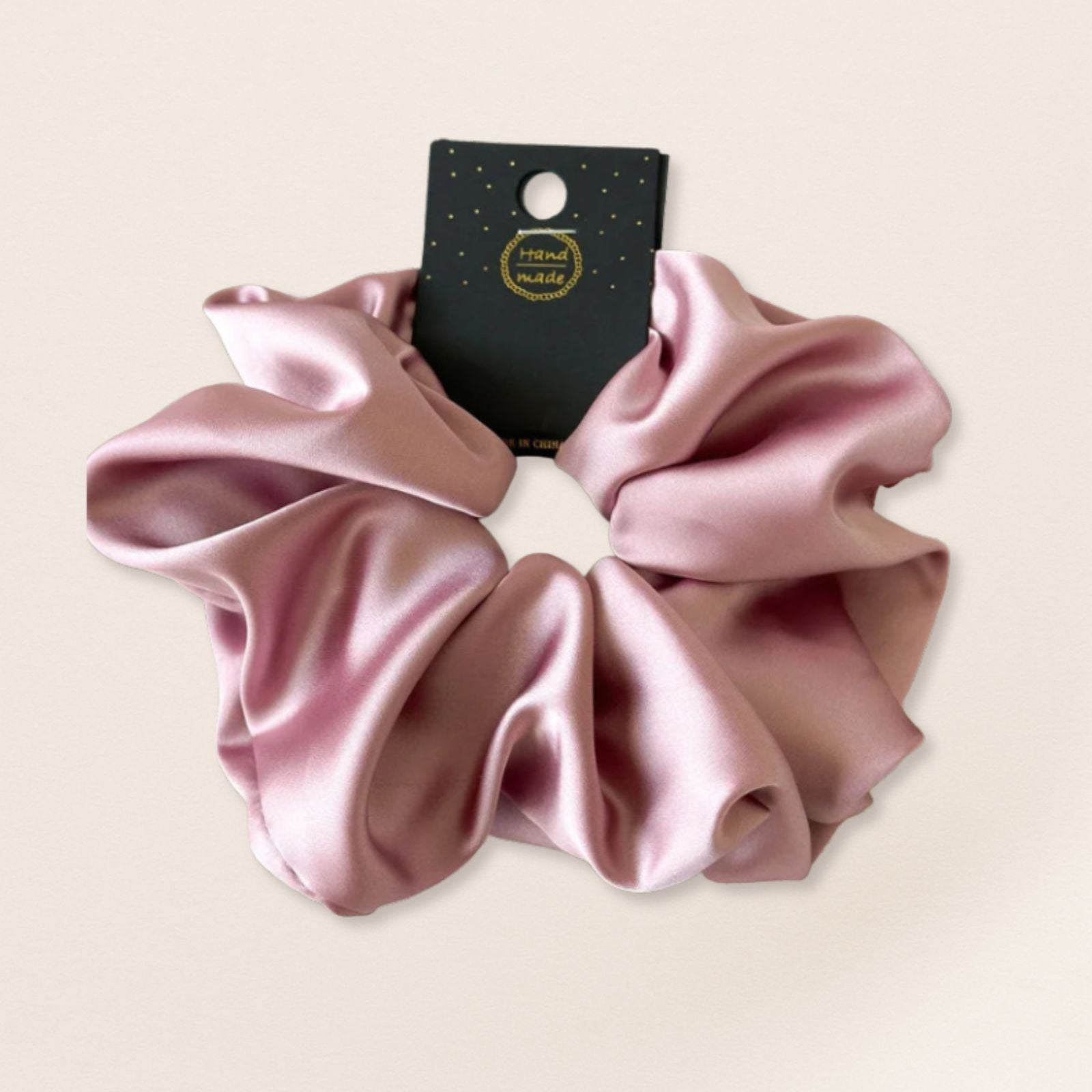 Pink satin scrunchie for fine hair on a beige background