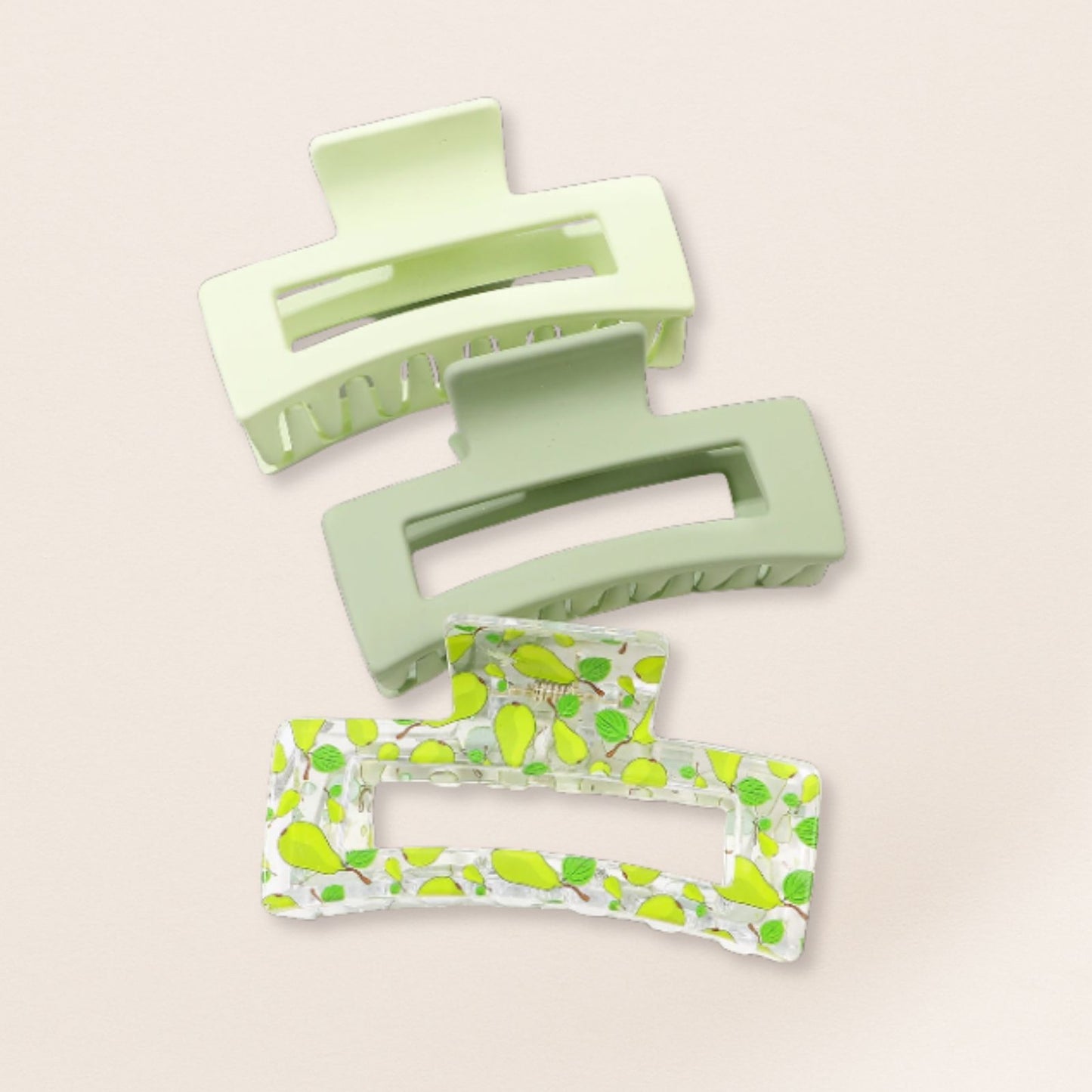 Two green hair clips with green patterns on a beige background