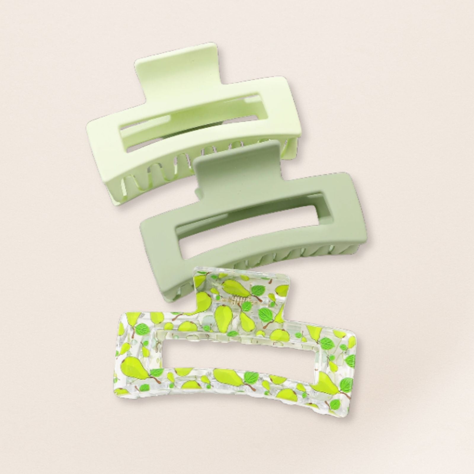 Two green hair clips with green patterns on a beige background