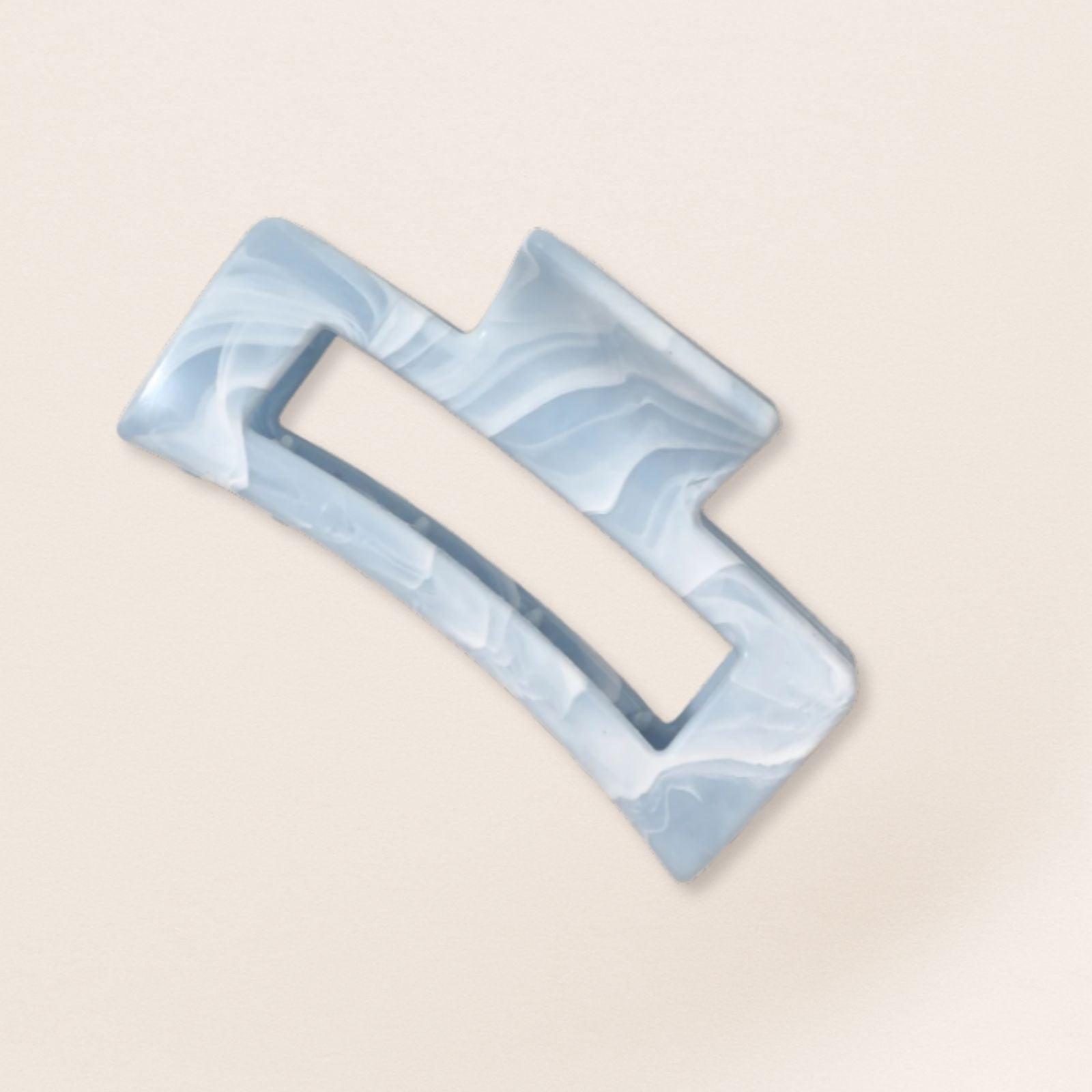 Marble-patterned blue and gray claw clip for fine hair on a beige background