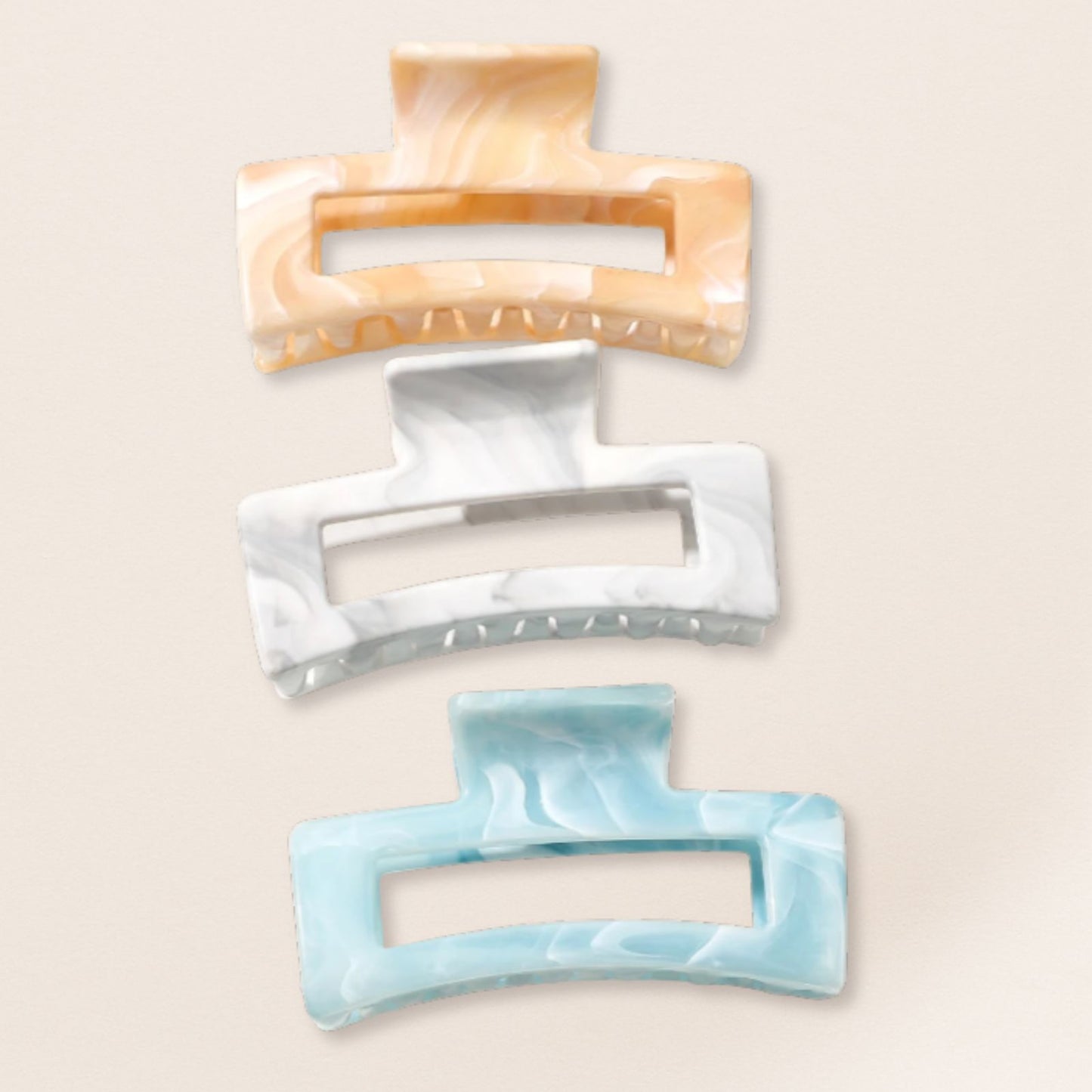 Three rectangular hair clips in beige, white, and light blue on a beige background