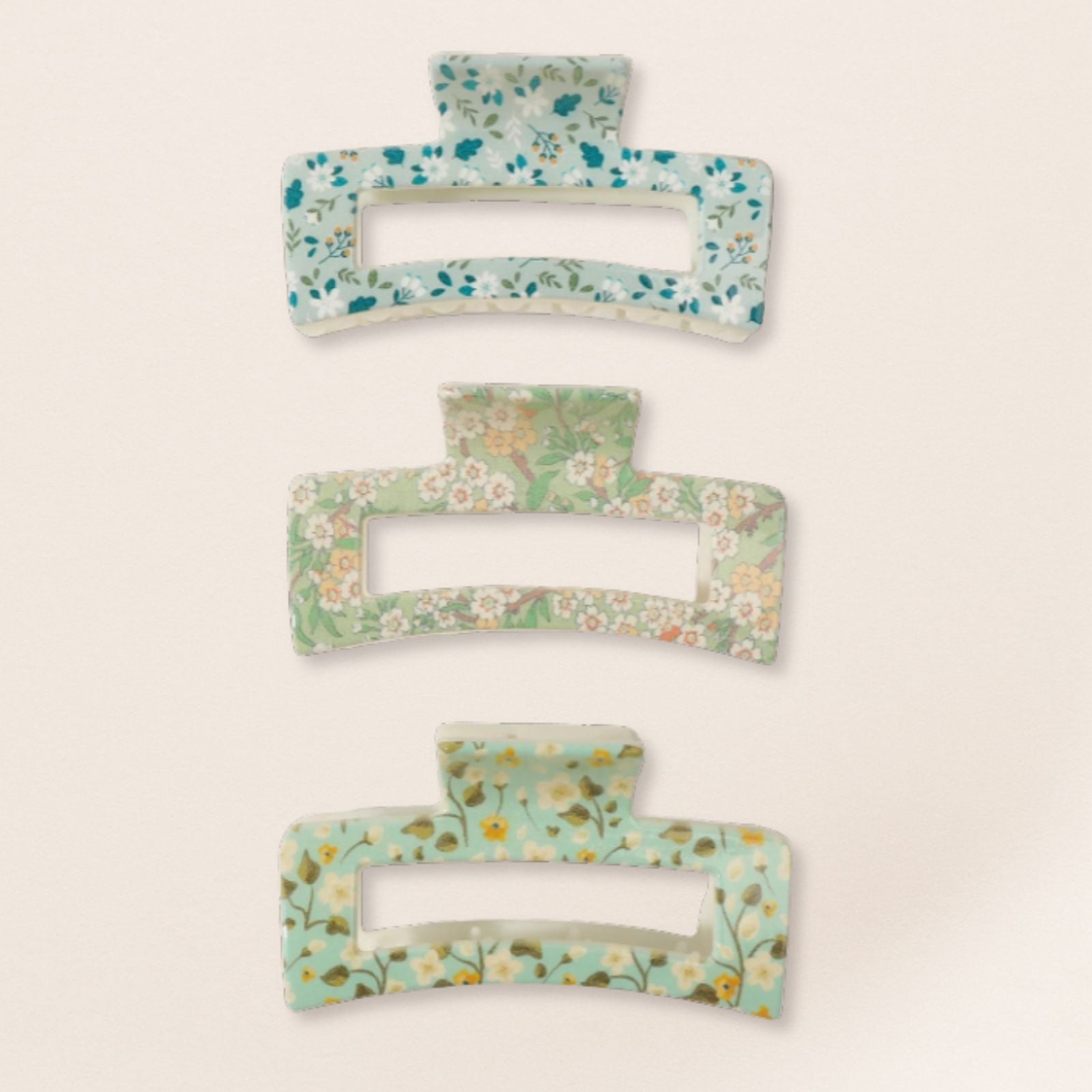 Set of three floral-patterned hair clips on a beige background