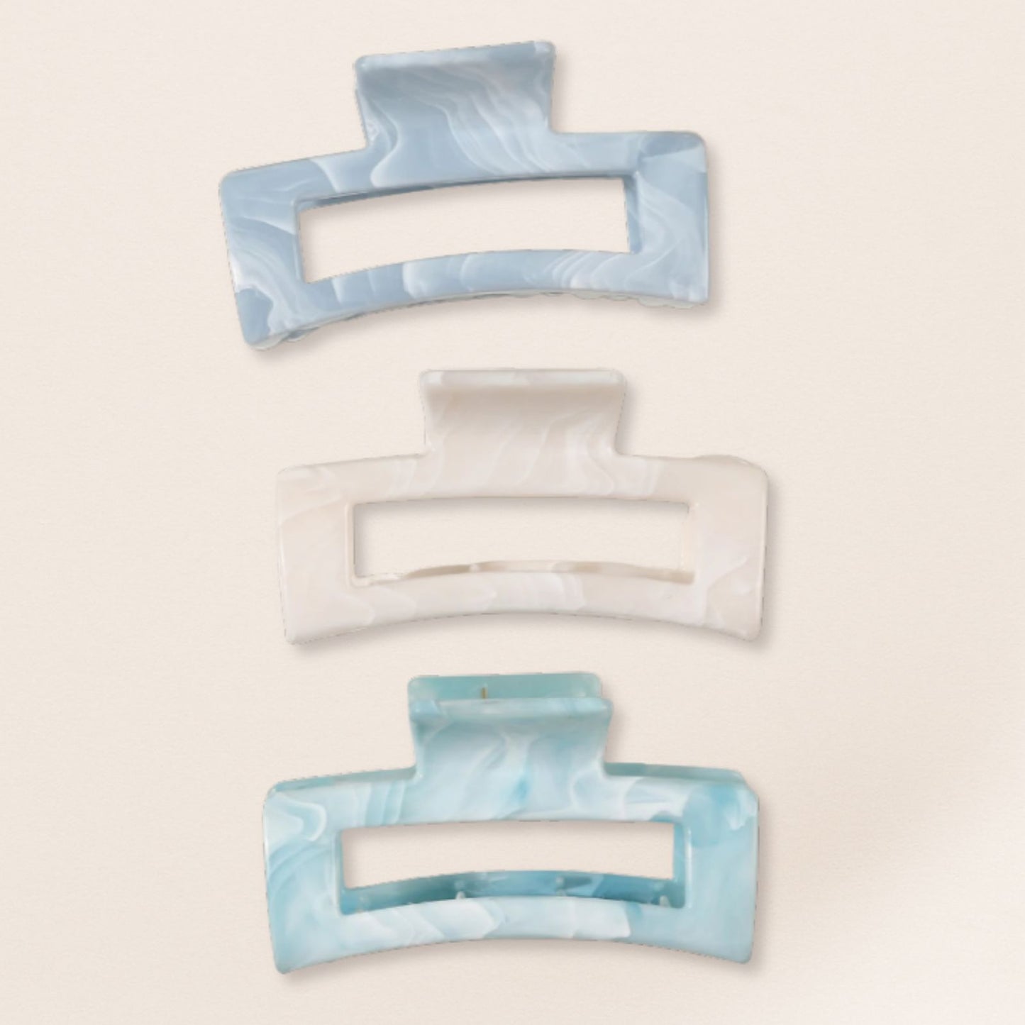 Set of three marbled blue and white hair clips on a beige background