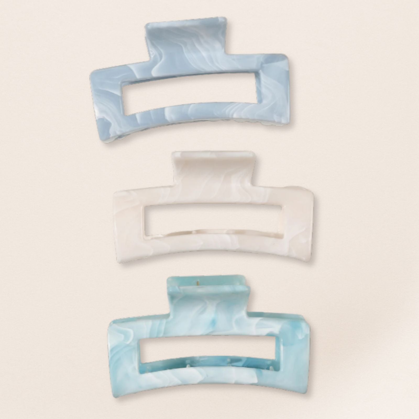 Set of three marbled blue and white hair clips on a beige background