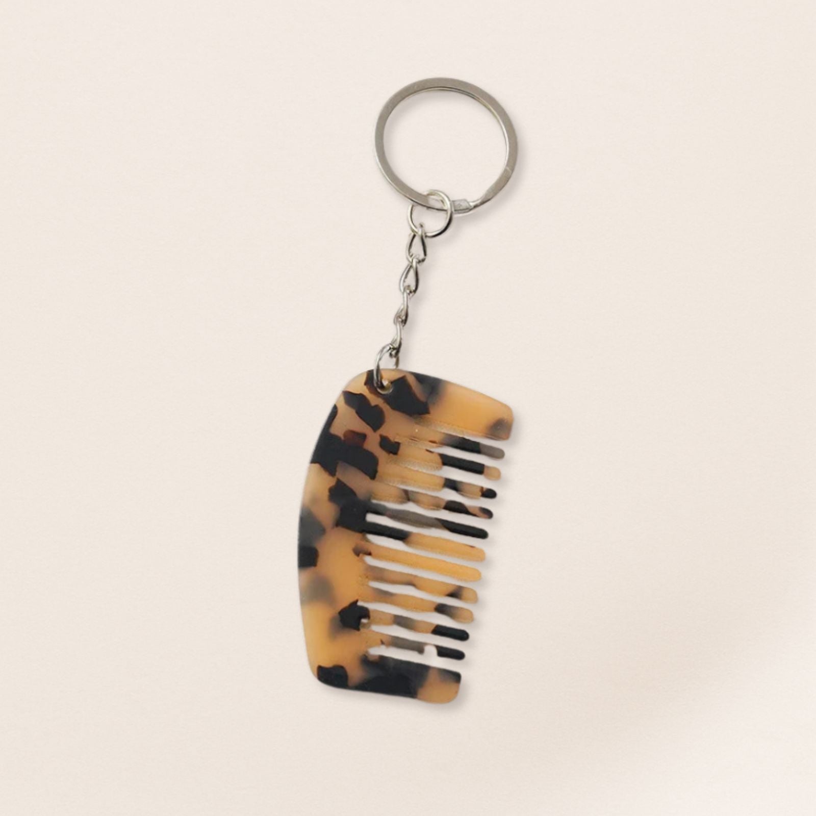 Tortoiseshell-patterned comb keychain on a beige background