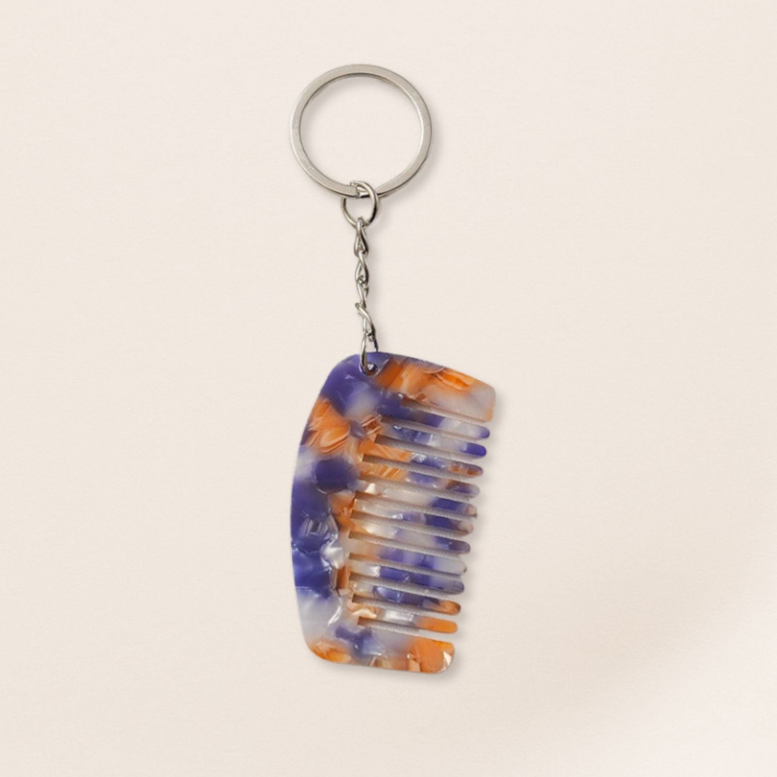 Colorful comb-shaped keychain on a beige background