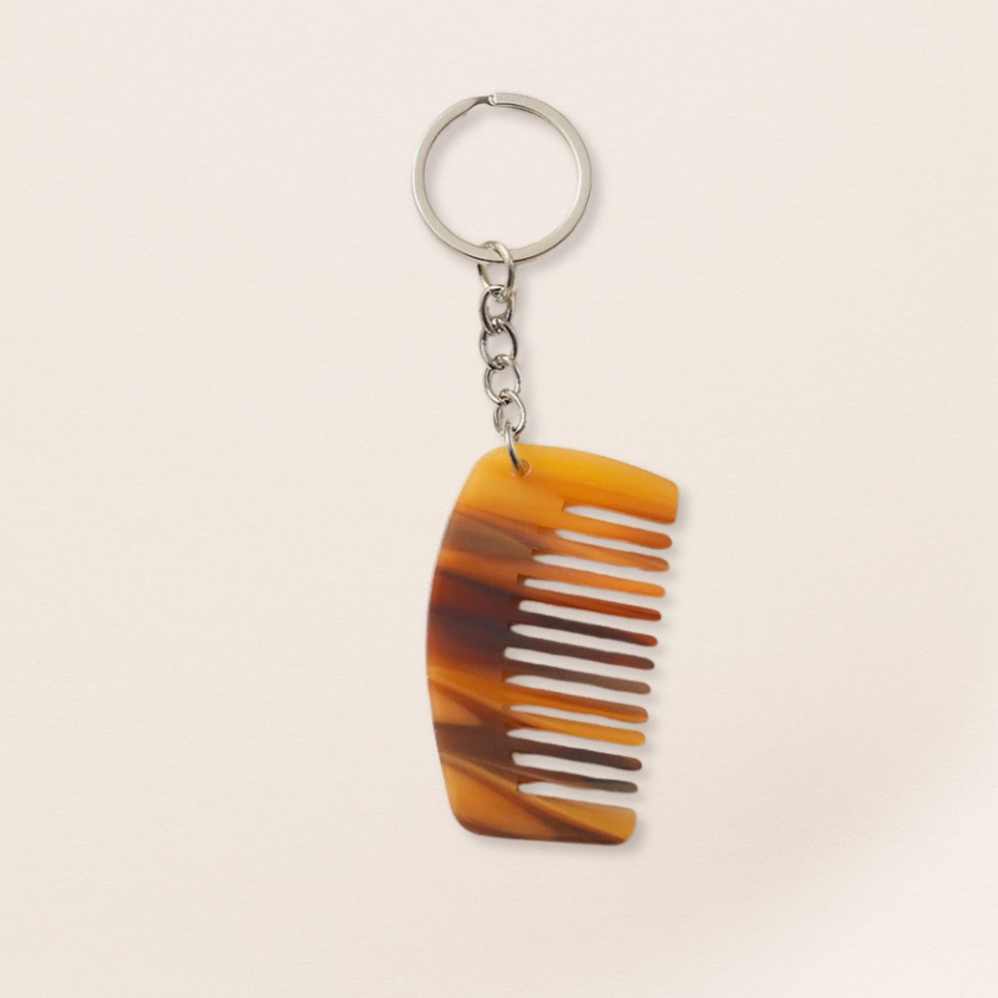 Mini brown marbled comb keyring with silver chain on a beige background.