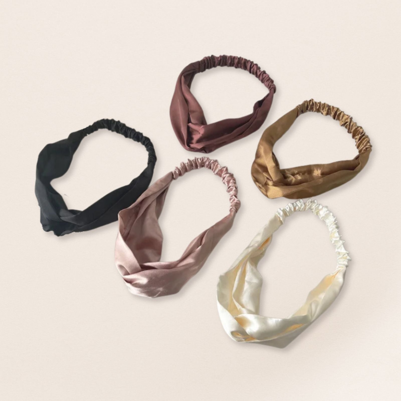 Five satin headbands in various colours on a beige background