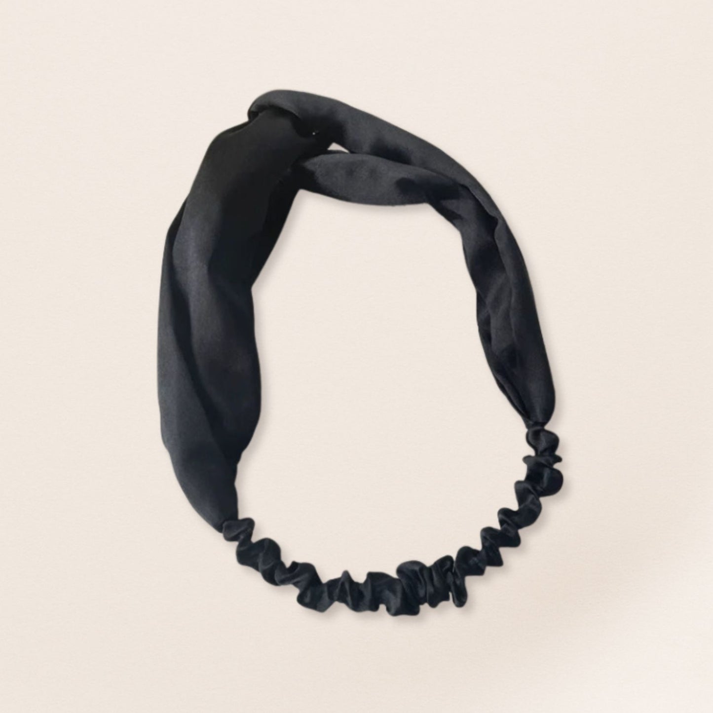 Black satin headband on a beige background