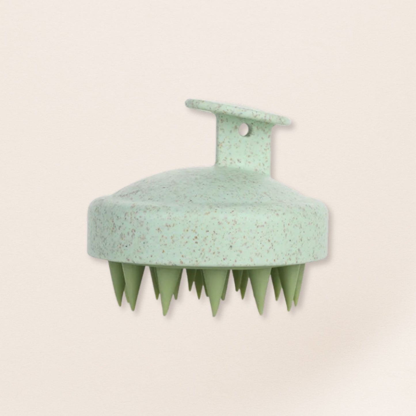 Green scalp massager on a beige background