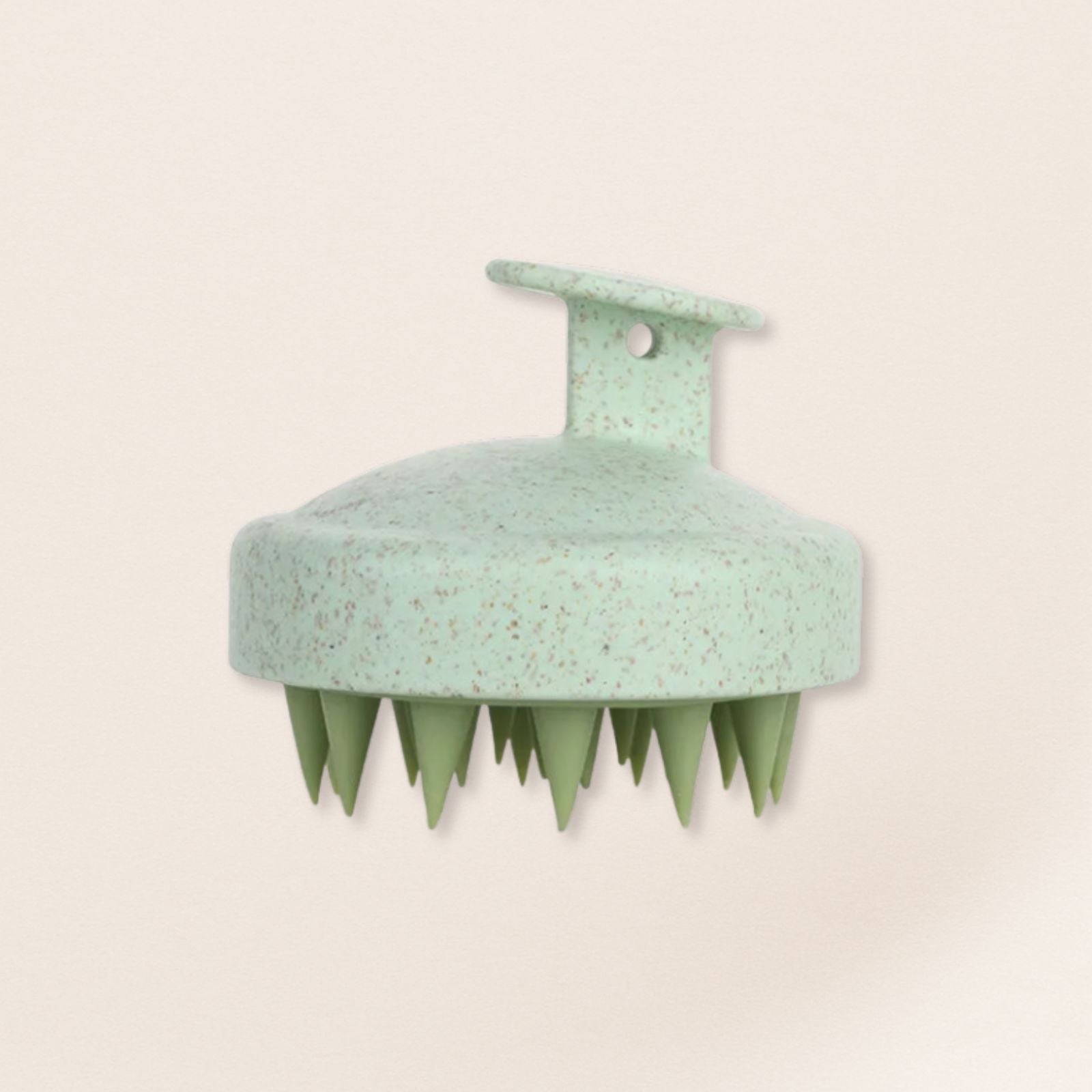 Green scalp massager on a beige background