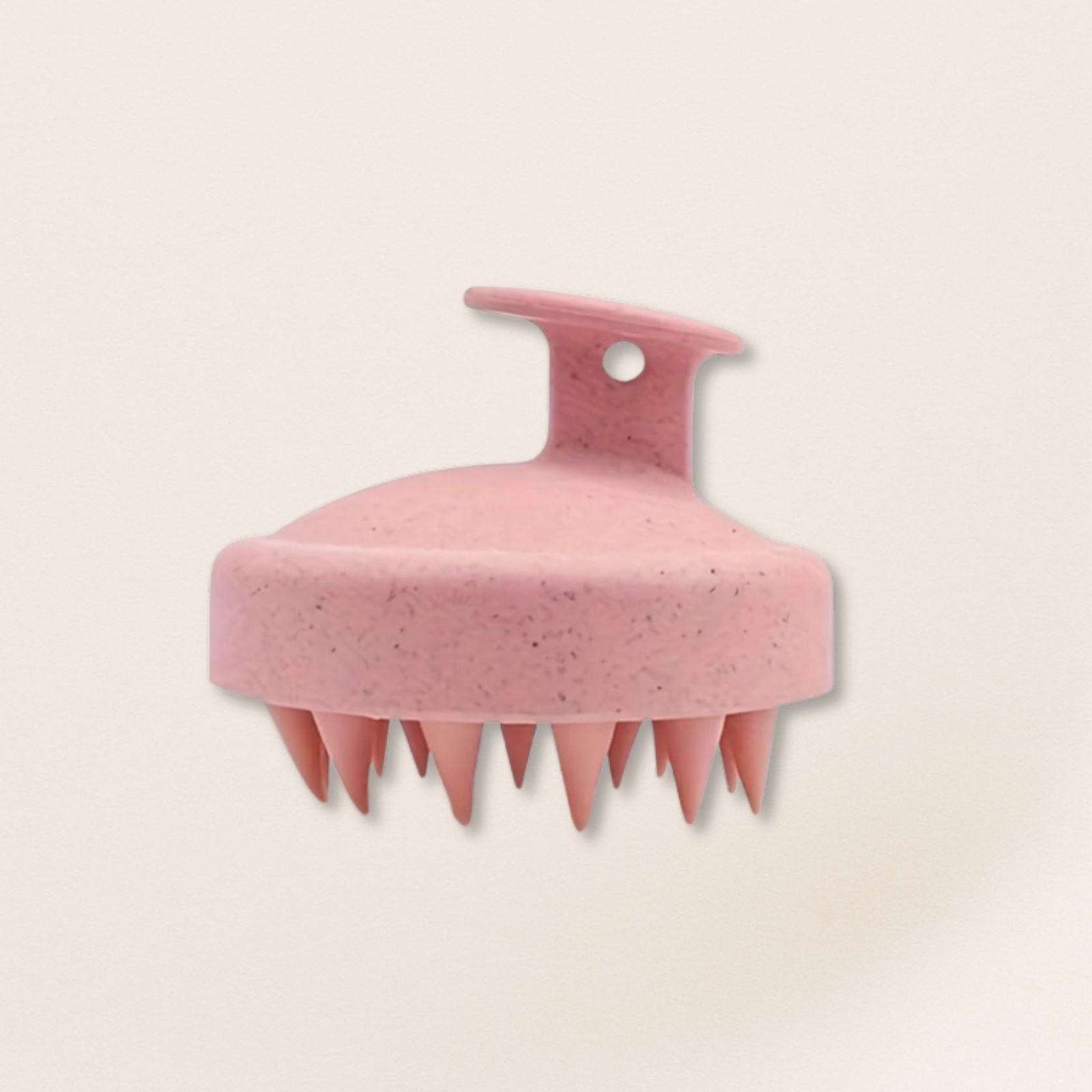 Pink scalp massager on a beige background