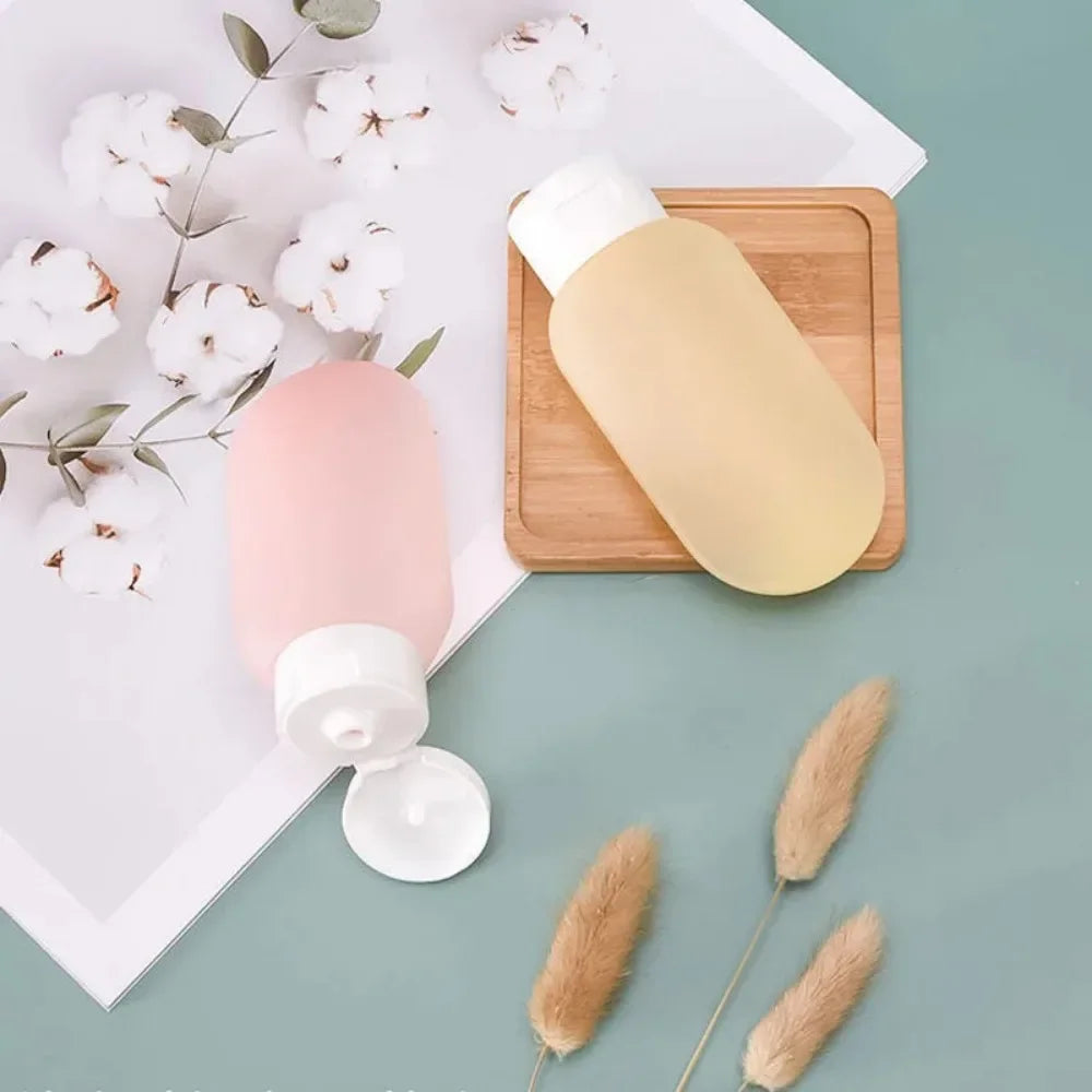 Two bottles with pump dispensers on a light green surface with cotton flowers and dried plants.